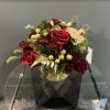 Red roses in a gold ornament-shaped container with pine and gold accents