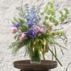 Bouquet of purple, pink, and blue flowers in a clear glass vase