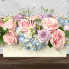 Pastel roses and hydrangeas arranged in a white box