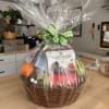 Gift basket of chocolates and snacks wrapped in clear cellophane with a green ribbon