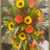 Tall arrangement of orange roses and sunflowers with dried grasses