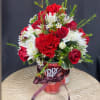 Red and white flower arrangement in a Dr Pepper can with a ribbon