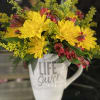 Yellow and red flowers arranged in a white mug