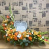 Orange and white floral arrangement with a heart memorial plaque