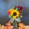 Sunflower bouquet in a glass vase with orange and burgundy flowers