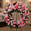 An open wreath with a mixture of lavender daisies, pink carnations, stargazer
