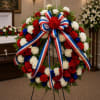 A Round open wreath, includes red and white carnations, blue statice and