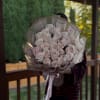 Bouquet of pale pink roses wrapped in patterned paper