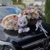 Two pastel flower arrangements with a plush bunny on a car hood