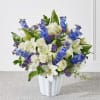 White lilies and roses with blue and purple flowers in a white vase