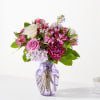 Pink and white mixed flower bouquet in a purple glass vase