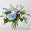 Blue hydrangea and white rose arrangement in a clear glass vase