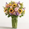 Bouquet of sunflowers, pink roses, and purple flowers in a glass vase