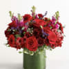 Red roses and mixed red flowers in a green glass vase