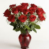 Red roses arranged in a red glass vase with baby's breath