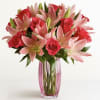 Pink lilies and red roses in a pink glass vase