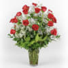 Red roses arranged in a clear glass vase with white filler flowers
