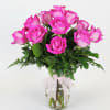 Pink roses in a clear glass vase with a white ribbon