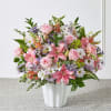 Pink roses and lilies arranged with white daisies in a white vase.