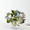 White roses and blue flowers in a clear glass vase
