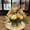White and peach floral basket with roses, lilies, and an angel figurine.