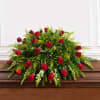 Red roses arranged in a low, full centerpiece with mixed greenery