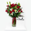 Red roses and white lilies in a glass vase with a ribbon