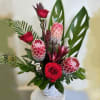 Red roses and pink protea in a white basket vase