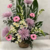 Pink and lavender flowers arranged in a wicker basket