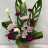 Basket arrangement with pink and purple flowers and white calla lilies