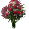 Red roses arranged in a clear glass vase with white filler flowers