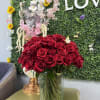 100 BEAUTIFULL RED ROSES ARRANGED NICELY IN A LARGE CLEAR VASE WITH