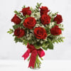 Bouquet of red roses with white filler flowers in a glass vase and pink ribbon