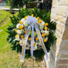Standing funeral wreath of yellow roses and white flowers with a ribbon