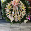 Large pink and white funeral wreath on a stand with ribbons