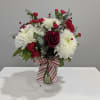 Red and white bouquet in a glass vase with a striped ribbon