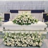 White floral funeral spray arranged around a white casket