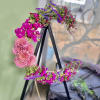 Floral wreath with pink and purple blooms on a black stand
