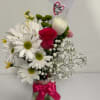 Bouquet of white daisies and a pink rose in a glass vase with a pink ribbon