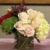 Bouquet of pale roses, hydrangea, and green filler in a glass vase