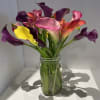 Bouquet of colorful calla lilies in a clear glass jar