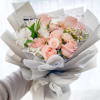 Hand-tied bouquet of pale pink roses and white flowers wrapped in gray paper
