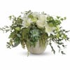 White roses and lilies in a low ceramic vase with trailing greenery