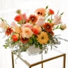 Mixed bouquet of peach, coral, and white flowers in a clear glass vase