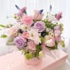 Pink and lavender bouquet with roses, carnations, and daisies in a round box