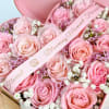 Pink roses arranged in a heart-shaped box with a ribbon