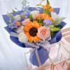Bouquet of sunflowers, roses, and pastel flowers wrapped in blue paper