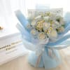 Bouquet of white roses and small daisies wrapped in pale blue paper