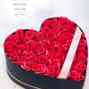 Heart-shaped box filled with red roses and a ribbon