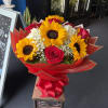Bright sunflowers, vivid red roses and white accents wrapped in bold red